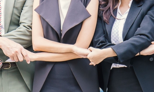 a row of business people crossing arms and holding hands